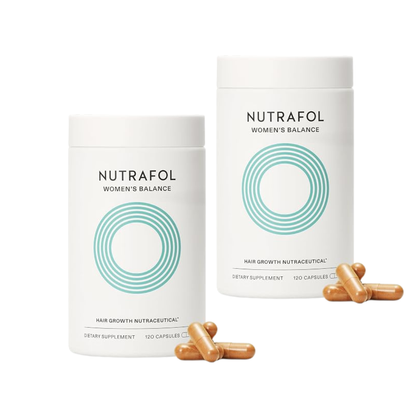 Two white Nutrafol Women's Balance supplement bottles on a white background, with several tan capsules placed in front.